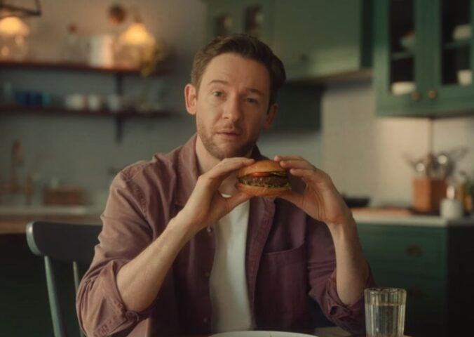 Screengrab from the new Beyond Meat advertisement shows someone eating a plant-based burger in a kitchen