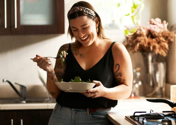 A woman eating a bowl of longevity superfood beans in a kitchen