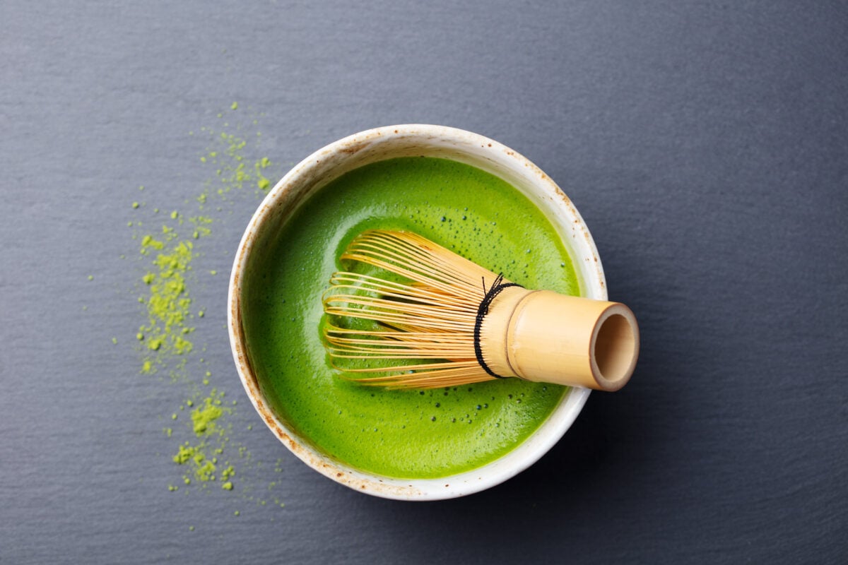 Photo shows a bowl of matcha tea with a bamboo whisk