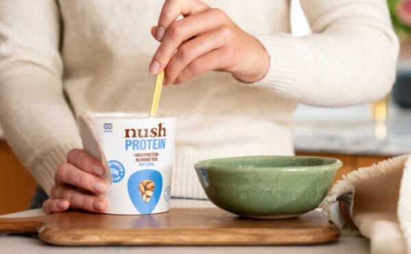 A person spooning a Nush high protein, soy-free yogurt