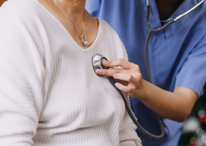 Photo shows a Dr or other healthcare professional using a stethoscope on a patient