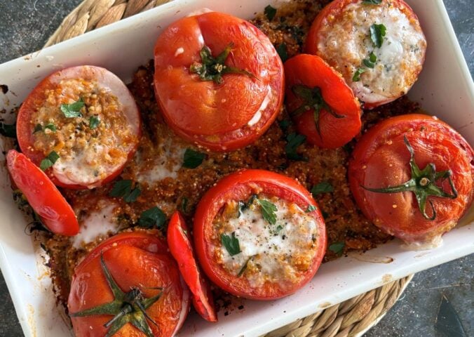 A tray of quinoa stuffed tomatoes with plant-based feta